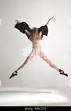 Junge schöne Tänzerin in beige Badeanzug tanzend auf grauem Hintergrund Stockfoto