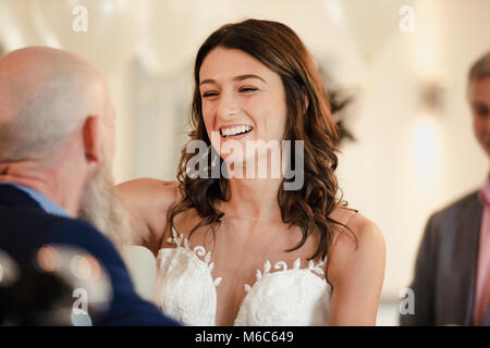 Schöne Braut ist in einem Tanz mit ihrem stolzen Vater. Sie werden lachen mit ihre Arme um einander. Stockfoto