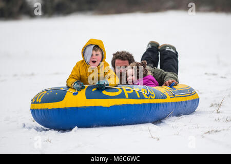 Phil Rogers und Kinder Rocco und Ruby Schlitten mit einem Beiboot im Batheaston in Somerset nach starkem Schneefall. Tier aus dem Osten, Sturm Emma. Stockfoto