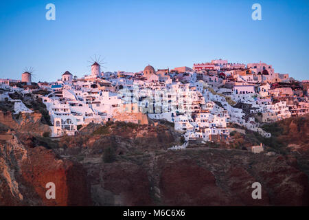 Wunderschöne Aussicht auf Dorf Oia, Santorini Island mit traditionellen Häusern und Windmühlen im Abendlicht Stockfoto