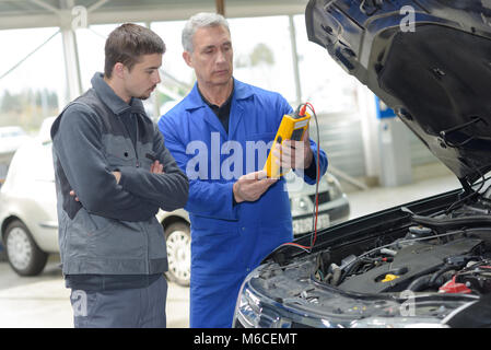 Schüler mit Lehrer, die Reparatur eines Autos während der Lehrzeit Stockfoto