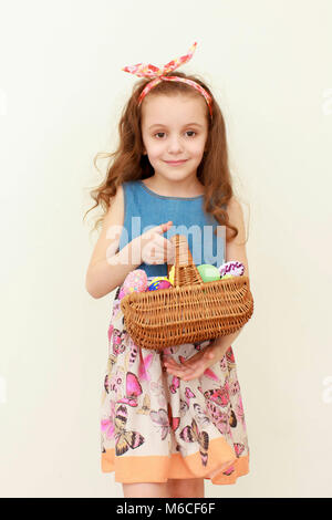 Portrait von kleinen Mädchen, dass Ostern Korb bemalte Eier. Portrait von Ostern kleines Mädchen Holding bemalte Eier. Kind mit Ostern Korb holida Stockfoto