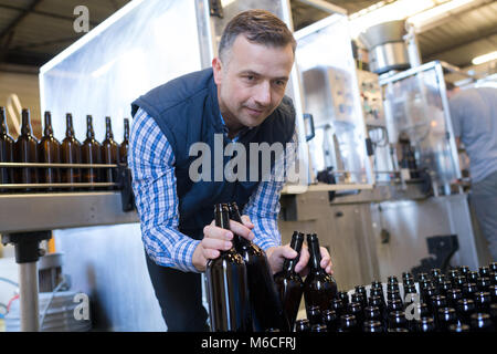 Brewer Abfüllung von Bier in der Flasche aus dem Tank an der Brauerei Stockfoto