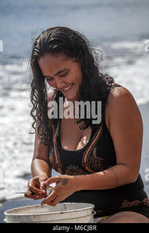 Frau, polynesische, lacht, reinigt Fisch am Strand, Badeanzug, Tahiti, Französisch-Polynesien Stockfoto