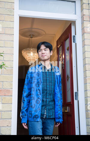 Eine asiatische Student verlässt seine Schüler Unterkunft durch die vordere Tür Stockfoto