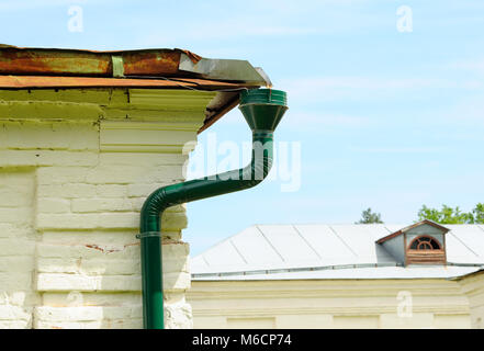 Grüne Regenrinne mit Fallrohr auf einer weißen Wand Stockfoto