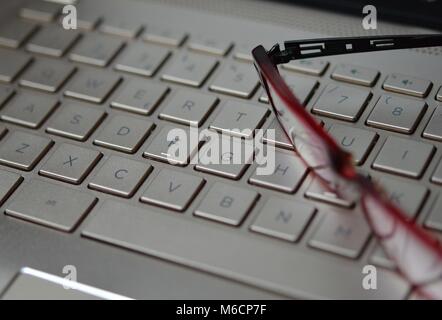 Müde Brillen auf einem Bronzefarbenen Laptop Tastatur Stockfoto