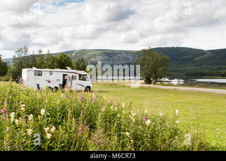 Große Reisemobil auf grünem Gras geparkt in der Nähe von einem See in Skandinavien. Stockfoto