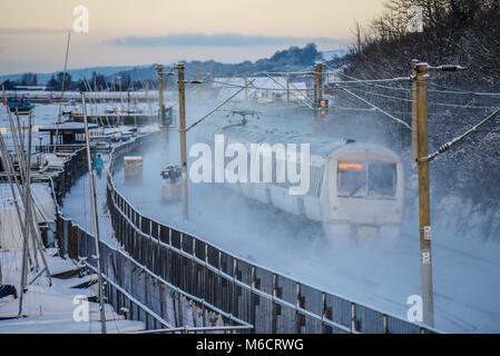 C2C-Eisenbahn Zug mit Geschwindigkeit durch Schnee bedeckt, werfen Wolken von Schnee. Stockfoto