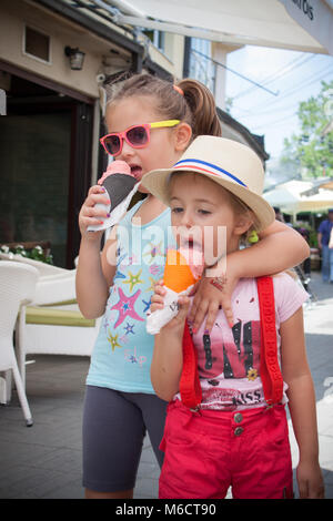 Porträt von zwei entzückende Kinder essen bunte Eis im Freien. Stockfoto