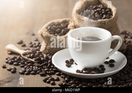 Tassen heißen Kaffee mit Rauch und Kaffeebohnen auf alten hölzernen Hintergrund Stockfoto
