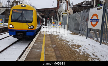 LONDON, Großbritannien - 2. März: EIN S-Bahn Zug Ansätze einer Station mit Titel mit Schnee bedeckt nach schwerem Schneefall über Nacht als Sturm Emma und "das Tier aus dem Osten "Bär auf dem Vereinigten Königreich am 1. März 2018. Ein gelbes Warnsymbol wurde durch das Department Met in einigen Bereichen erteilt, da das Wetter Flughafen Schließung und Schiene Stornierung um das Land verursacht. Quelle: David Mbiyu/Alamy leben Nachrichten Stockfoto