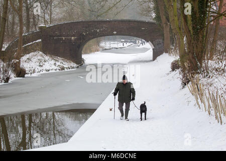 Nach kaltem Wetter im März ein Mann seinen Hund der Coventry Canal in Atherstone, der gefroren war und durch Schnee Kredit abgedeckt: David Warren/Alamy leben Nachrichten Stockfoto