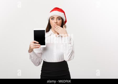 Geschäftskonzept - Junge kaukasier Business woman in Weihnachten Thema anzeigen digital Tablet mit überraschenden Gesichtsausdruck. Stockfoto