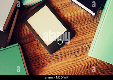 E-Book Reader und Bücher über Holz- Hintergrund. Ansicht von oben. Stockfoto