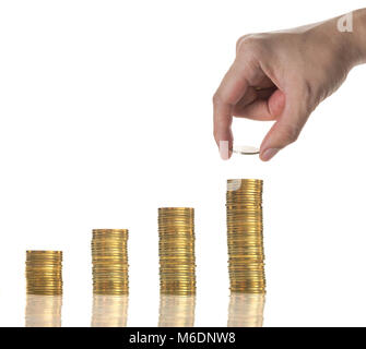 Hand und eine goldene Münze auf dem Stapel von Goldmünzen mit Saatgut, auf weißem Hintergrund, die Investitionen der Unternehmen Konzept Stockfoto