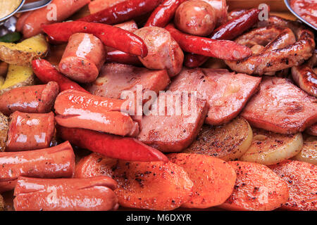 Verschiedene gebratene Würstchen, gegrillte Karotten, Zwiebeln, gegrillte Kartoffeln Stockfoto