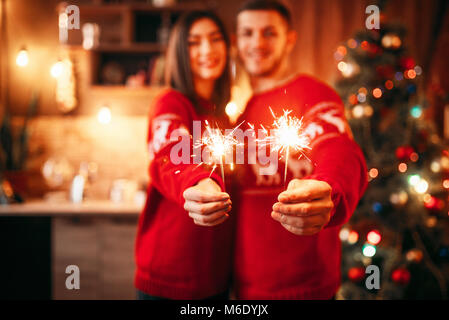 Liebe Paar hält Wunderkerzen in den Händen, Weihnachten romantische Feier. Mann und Frau feiern Weihnachten zusammen Stockfoto