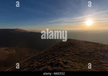 Kreuz auf dem Gipfel des Mt. Serrasanta (Umbrien, Italien), mit warmen goldenen Stunde Farben und die Sonne tief am Horizont Stockfoto