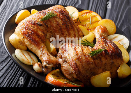 Hausgemachten BBQ: Gegrillte Hähnchenkeulen mit Orange, Zitrone, Zwiebeln, Knoblauch und Kartoffeln Close-up auf einem Teller auf den Tisch. Horizontale Stockfoto