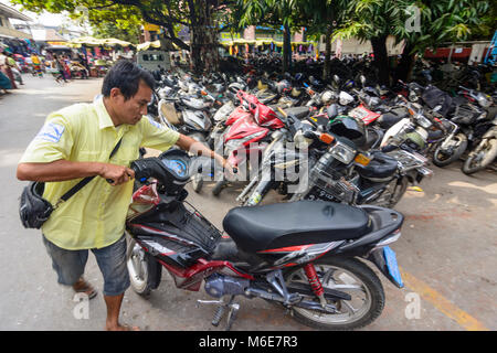 Mandalay: Motorrad Parkplatz attendant Bike in der rechten Stellung bewegt, Region, Mandalay, Myanmar (Birma) Stockfoto