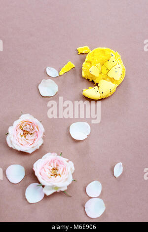 Gelbe Makronen und Blumen auf rosa Hintergrund zerquetscht. Ansicht von oben. Flach. Stockfoto
