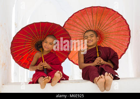 Junge Novizin buddhistische Mönche holding Sonnenschirme am Myatheindan Pagode (auch als Hsinbyume Pagode bekannt), Mingun, Myanmar (Burma), Asien im Februar Stockfoto