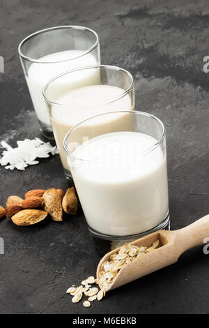 Vegan oat, Mandel, Kokosnuss Milch in Glas auf einem dunklen Hintergrund. Nicht-Molkerei Milch Stockfoto