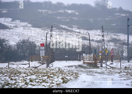 Unbeaufsichtigte Bahnübergang im Winter mit Schnee auf dem Boden. Unkontrollierte Tore in einem Feld. C2C-Linie durch Hadleigh Country Park. Hügel Stockfoto