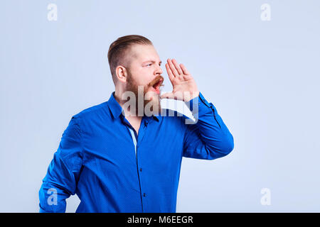 Bärtiger Mann in Freizeitkleidung auf grauem Hintergrund Shouts. Stockfoto