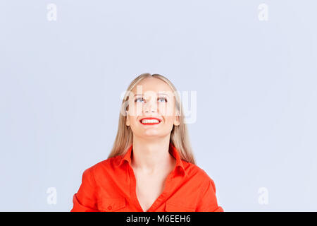 Blonde Frau in Freizeitkleidung an der Spitze mit positiven Emotionen auf grauem Hintergrund. Stockfoto