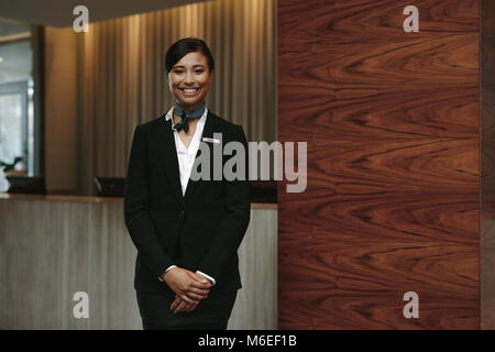 Portrait von Happy weiblich Rezeption stehen am Arbeitsplatz. Lächelnde Frau Rezeptionistin im Hotel arbeiten. Stockfoto