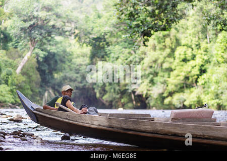 Alter Mann entspannen in traditionellen Holz- Boot auf dem Fluss in den ältesten Regenwald der Welt, Taman Negara, Malaysia Stockfoto