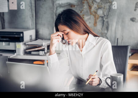 Frustriert asiatischen Geschäftsfrau Abdeckung ihr Gesicht mit beiden Händen und fühlen sich von der Arbeit am Laptop umgekippt auf dem Schreibtisch im Büro, Stress office lifes Stockfoto