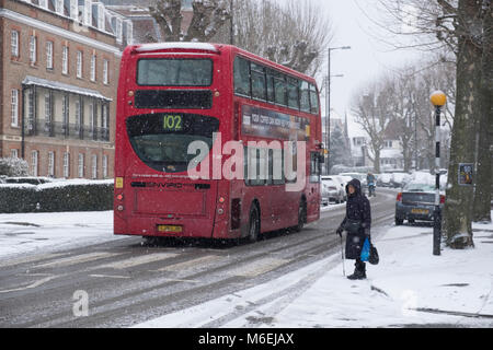 Eine Frau wartet, die Straße in Muswell Hill als "Tier aus dem Osten' kaltem Wetter und Schnee Ende Februar und Anfang März 2018 für die Stockfoto