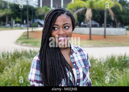 Afrikanische Frau mit Dreadlocks, seitlich im Freien im Sommer Stockfoto