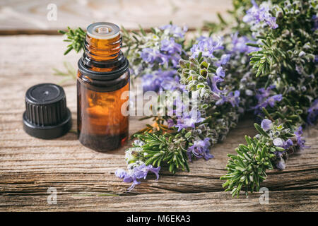 Rosemary wesentliches Öl und frischen blühenden Zweig auf einen hölzernen Tisch, Detailansicht mit Details Stockfoto