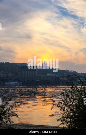 Blick auf den Sonnenuntergang über Saint Andrew's Church in Kiew, Ukraine. Dnipro River im Vordergrund Stockfoto