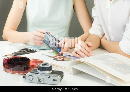 Neu verheiratet oder verlobt Paar sucht und wählt Bilder kleben Sie in die Hochzeit Album gedruckt Stockfoto