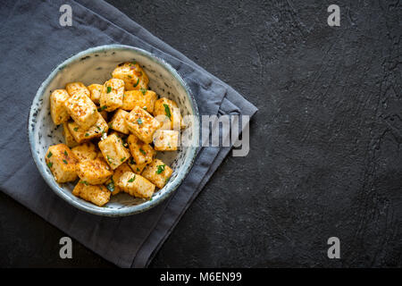 Rühren gebratener Tofu in eine Schüssel geben und mit Sesam und Grüns. Hausgemachte gesunde Vegane asiatische Mahlzeit - gebratenem Tofu. Stockfoto