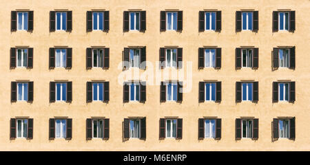 Italien, Rom. Holzfenster mit braunen Fensterläden auf einer pastellfarbenen Fassade Wohnhaus, Banner Stockfoto