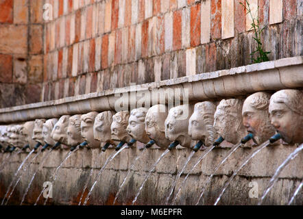 L'Aquila, Italien. Brunnen der 99 Wasserspeier. 13. jahrhundert Brunnen, wo das Wasser spritzt aus dem Mund der 99 geschnitzten Köpfen. Stockfoto