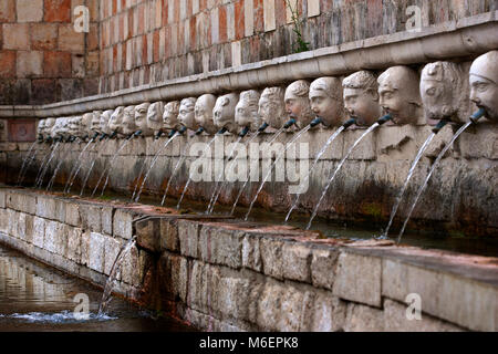 L'Aquila, Italien. Brunnen der 99 Wasserspeier. 13. jahrhundert Brunnen, wo das Wasser spritzt aus dem Mund der 99 geschnitzten Köpfen. Stockfoto