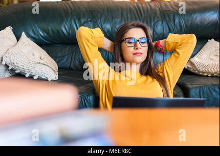 Frau sitzt auf dem Boden mit einem Laptop und Handy Kaffee zu trinken. Stockfoto