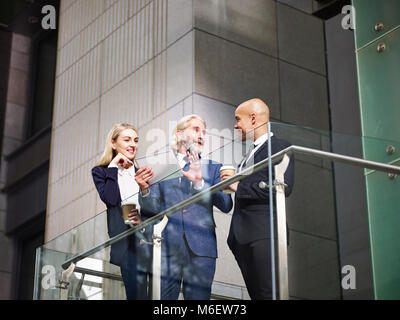 Multinationalen und multiethnischen corporate Menschen diskutieren Geschäft mit digitalen Tablet in der modernen Bürogebäude, Low Angle View. Stockfoto