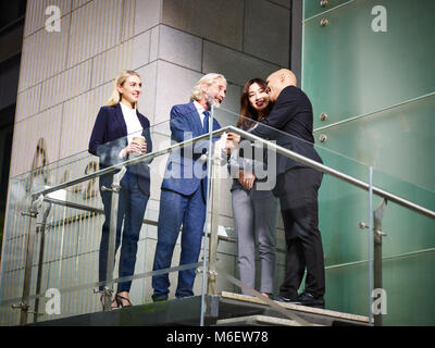 Senior Corporate Executive begrüßen Besucher auf der Treppe der modernen Bürogebäude, Low Angle View. Stockfoto