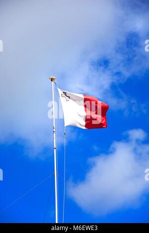 Die maltesische Flagge entrollt gegen einen blauen Himmel mit Fluffy Clouds, Gozo, Malta. Stockfoto