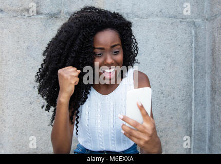 Afrika amerikanische Frauen, die guten Nachrichten am Telefon im Freien Stockfoto