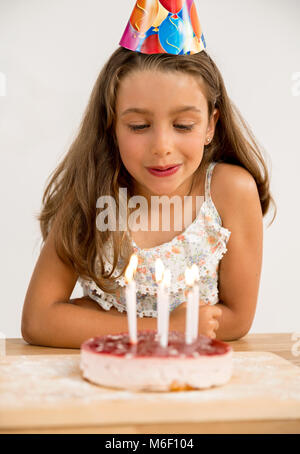 Schoß eines jungen Mädchens das Ausblasen der Kerzen auf der Geburtstagstorte Stockfoto