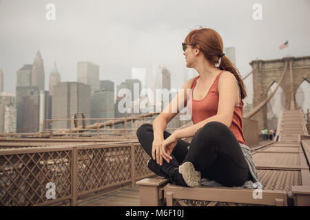 Frau sitzt auf der Brooklyn Bridge und suchen die Ansicht Stockfoto